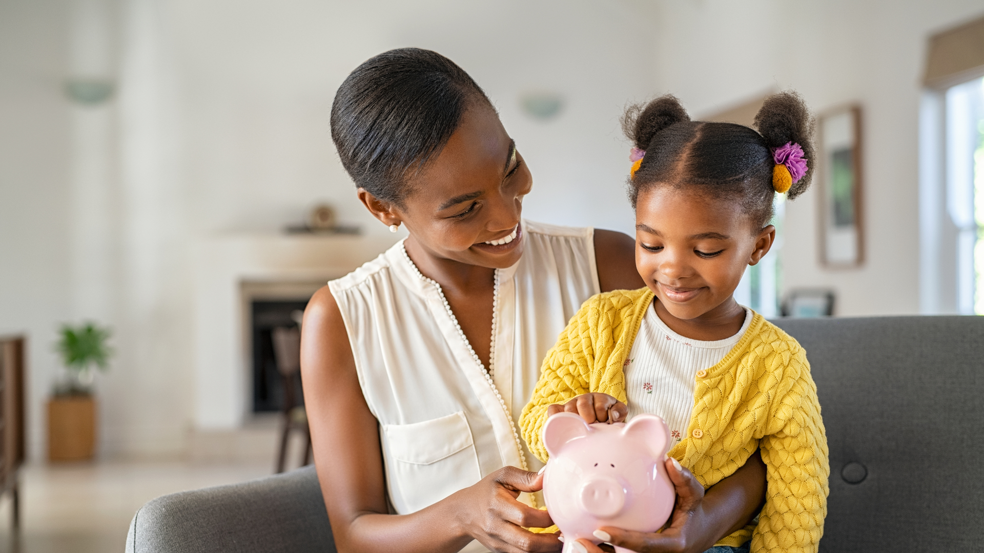 Black woman with daughter holding piggy bank