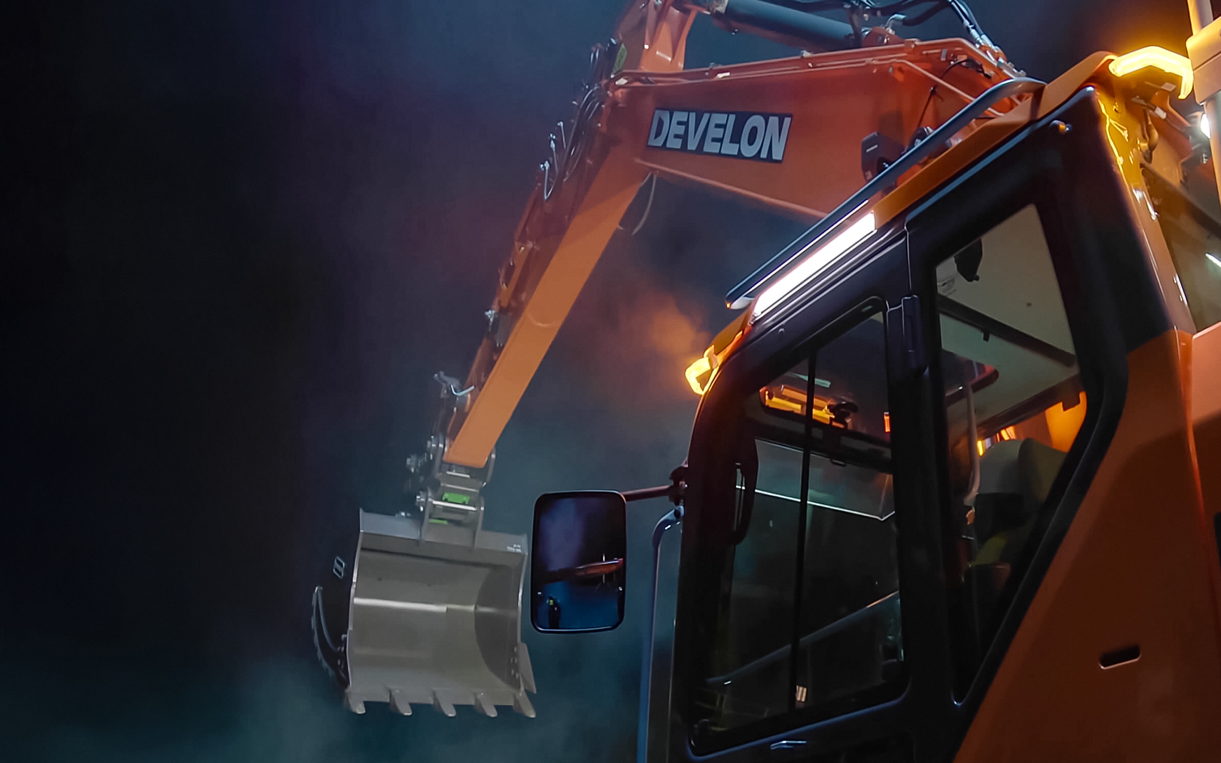  DEVELON -9 Series crawler excavator cab and raised bucket in a dark setting.