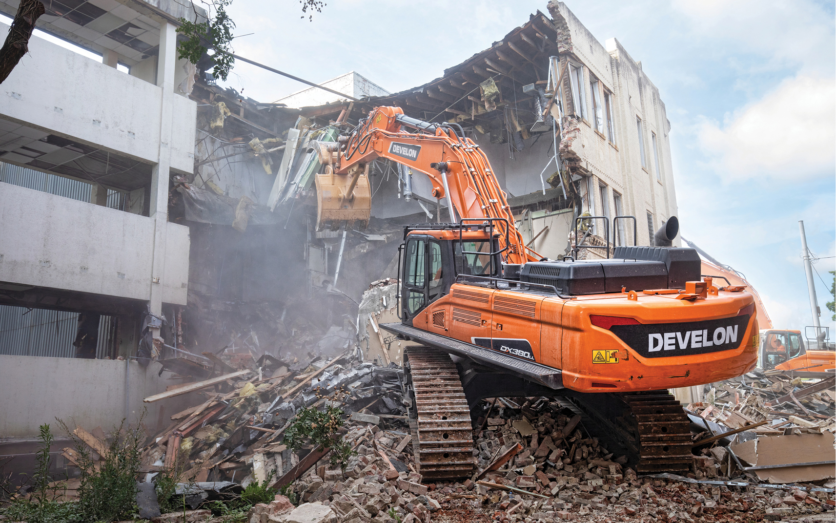 A DEVELON DX380LL road builder demoing a building.