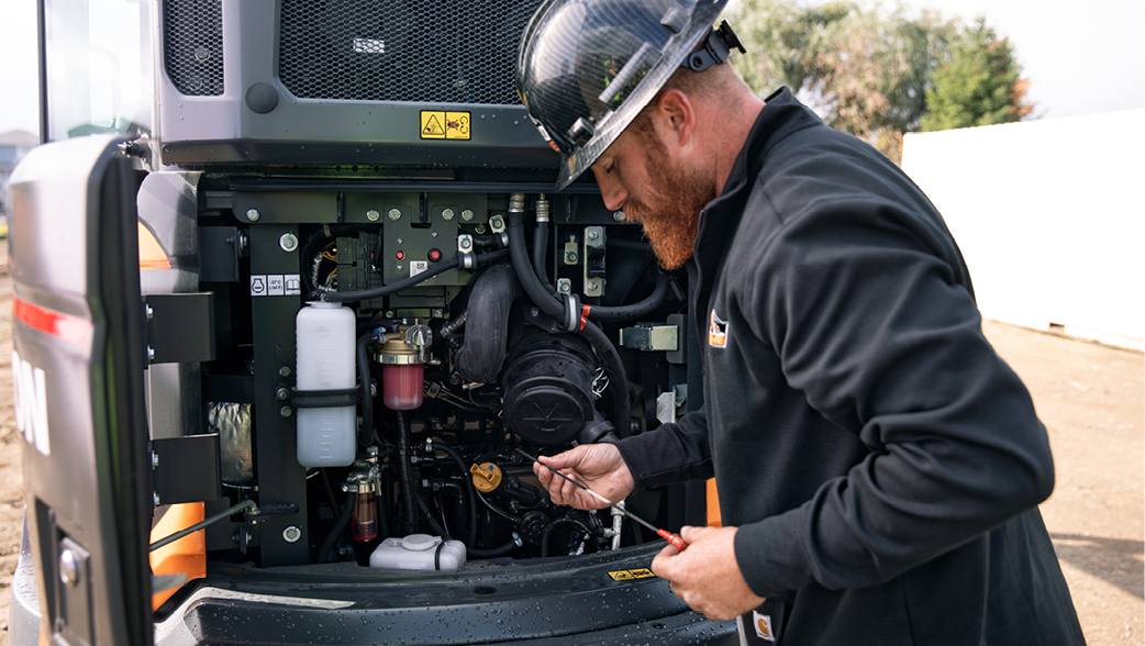 DEVELON certified technician checking the oil on a mini excavator.