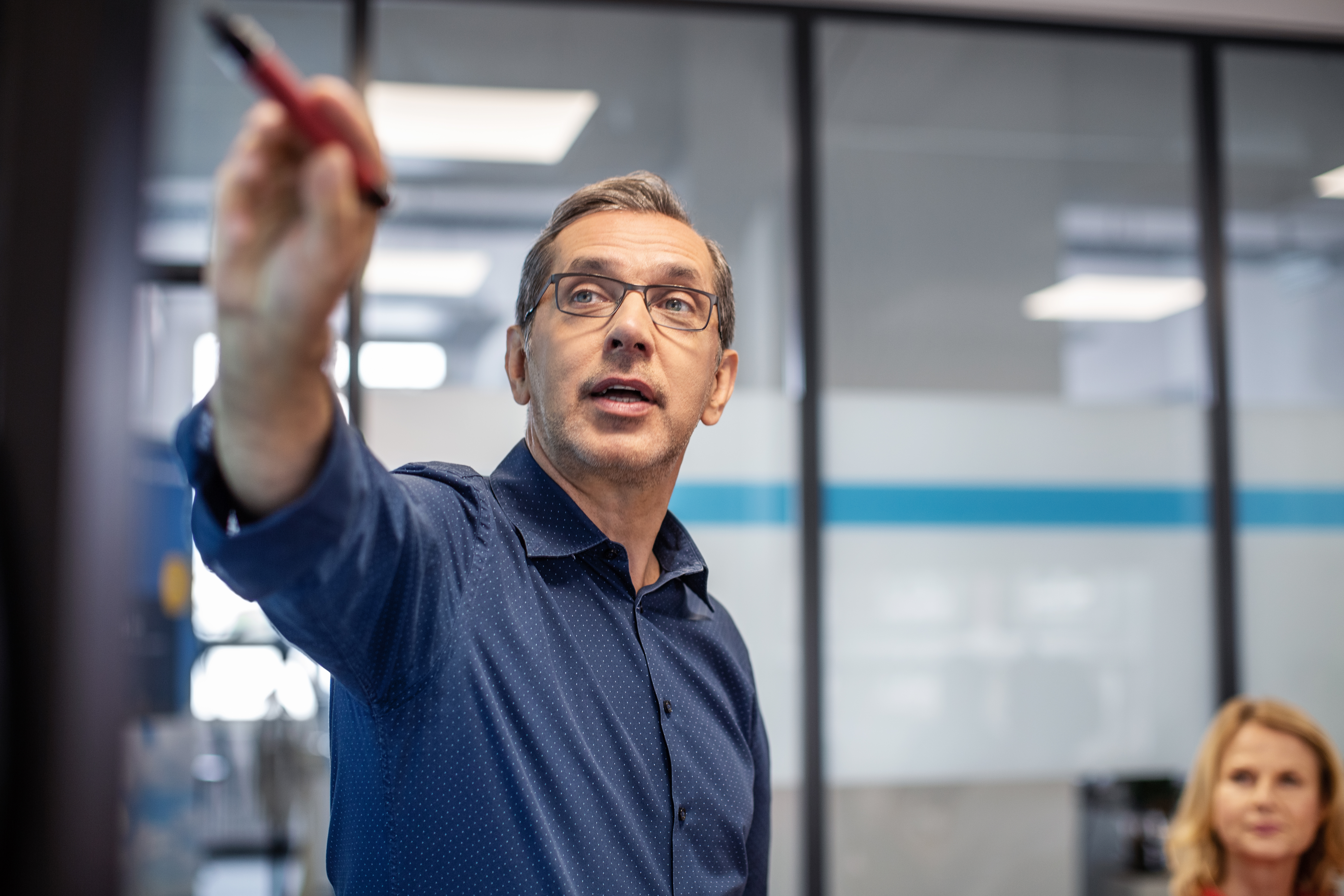 Visual learning aids in business collaboration as a man goes through a presentation with colleagues, pointing at a display.