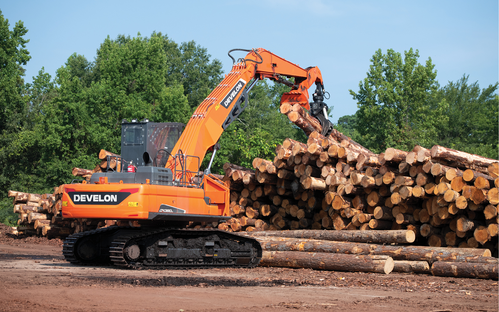 A DEVELON log loader uses a log grapple to lift timber at a sawmill in Arkansas.