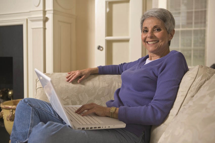 A woman smiles while scrolling through her laptop computer