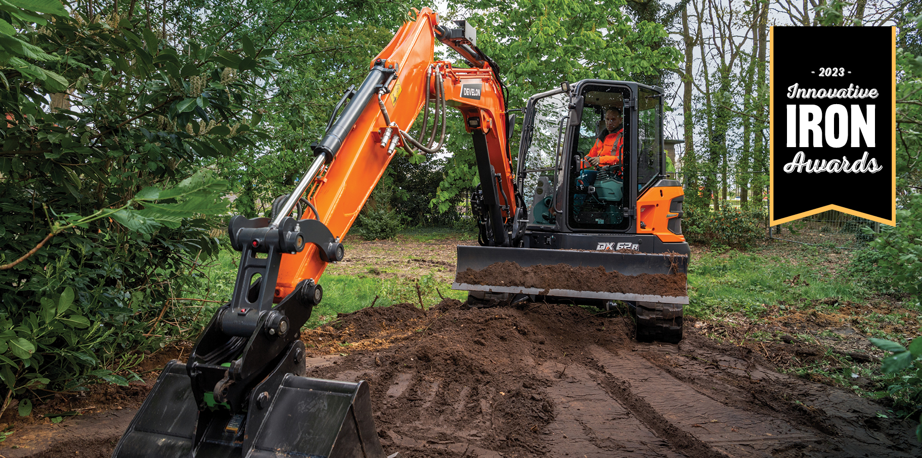 DEVELON DX62R-7 mini excavator digging dirt with a 2023 Innovative Iron Award graphic.