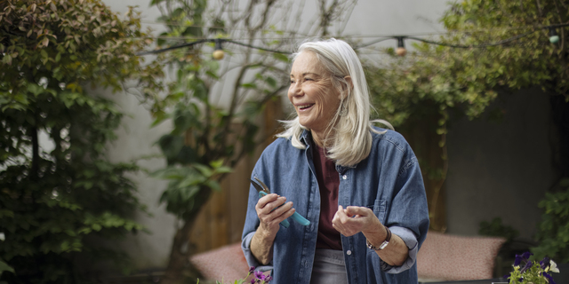 An elderly woman gardening on her balcony, at home