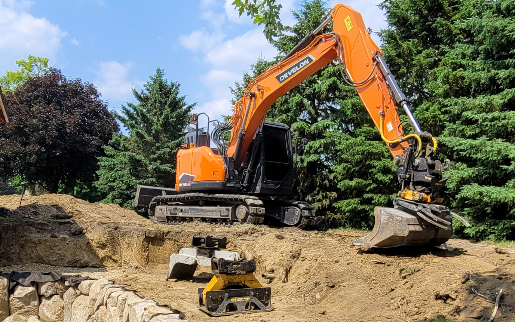 A DEVELON excavator with tiltrotator working on a job site.