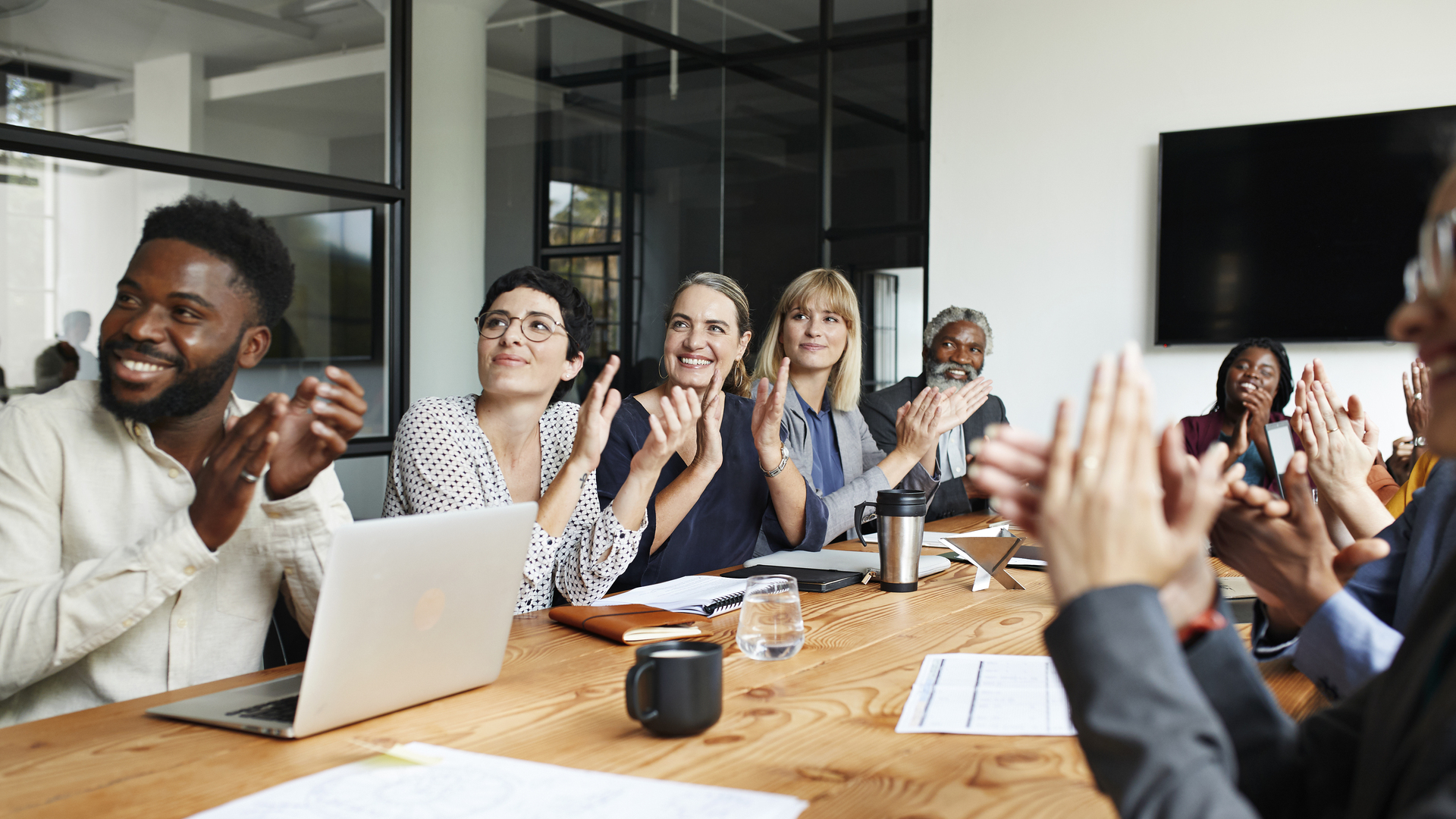 Executives clapping by table in office meeting