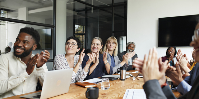 Executives clapping by table in office meeting