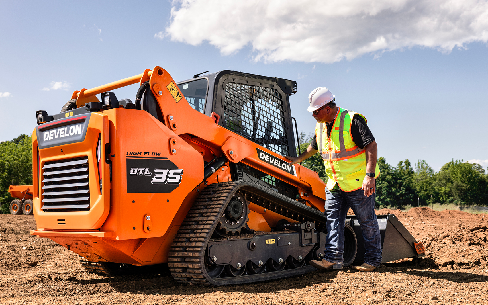 An operator inspecting a DEVELON DTL35 compact track loader.