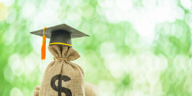 Education or student loan, financial aid and scholarship concept : Mortarboard or graduation cap on top of a US dollar cash bag. Depicting financial assistance for a student's tuition and other costs.