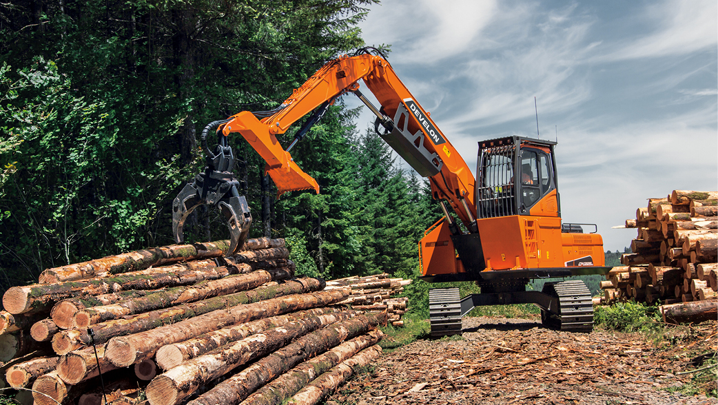 A DEVELON log loader moving a pile of trees on a job site.