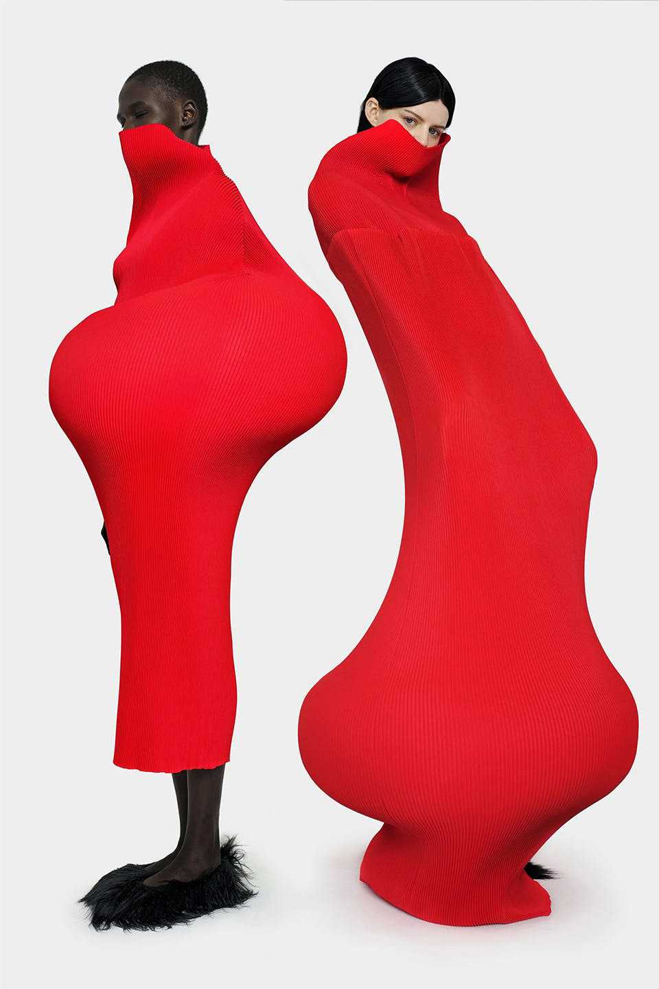 Models showcasing red garments featuring bold silhouettes and precise tailoring, key features of the MELITTA BAUMEISTER brand.
