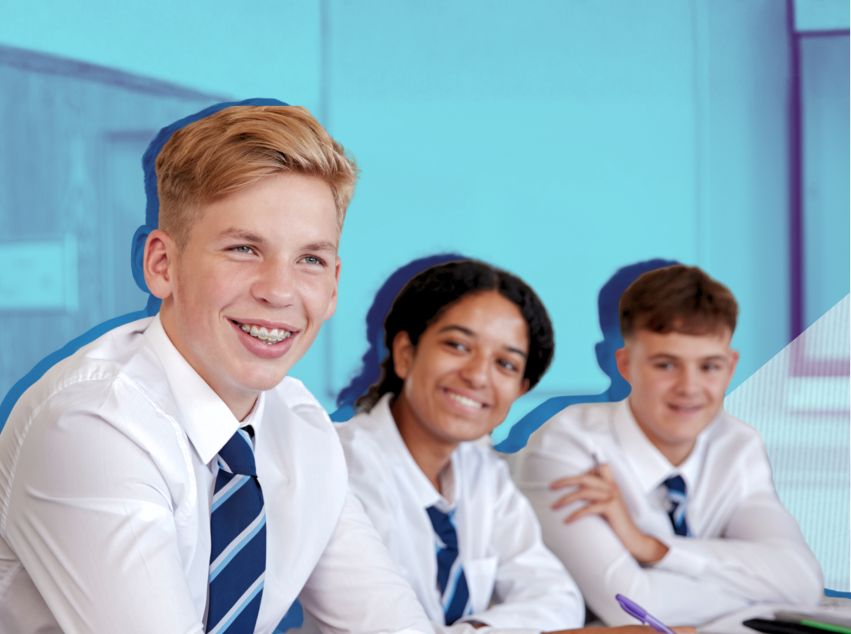 Teens in school uniform smiling as they sit at their desk