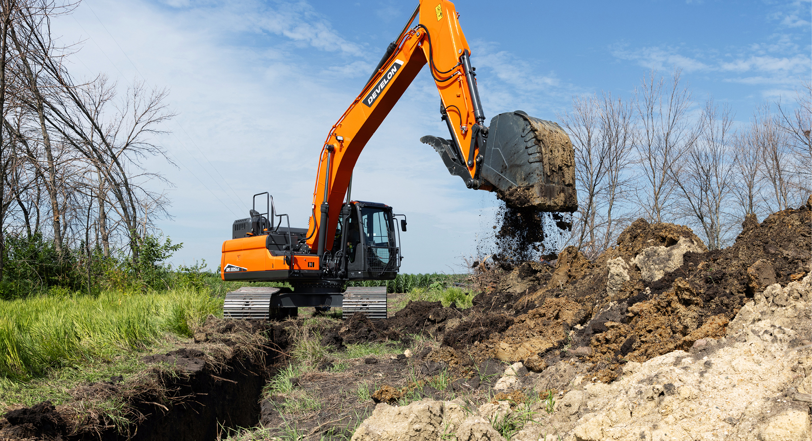 A DEVELON crawler excavator dumps dirt on a job site.