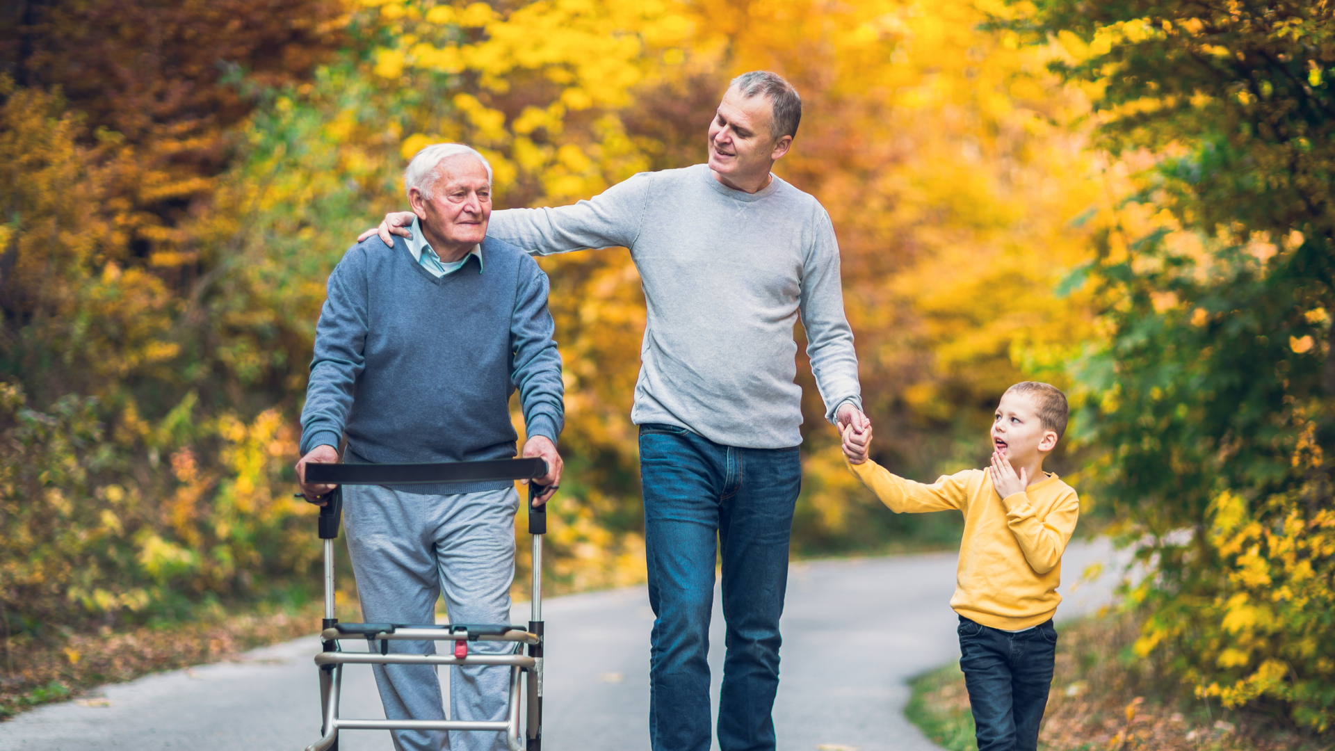 Elderly father adult son and grandson out for a walk in the park.