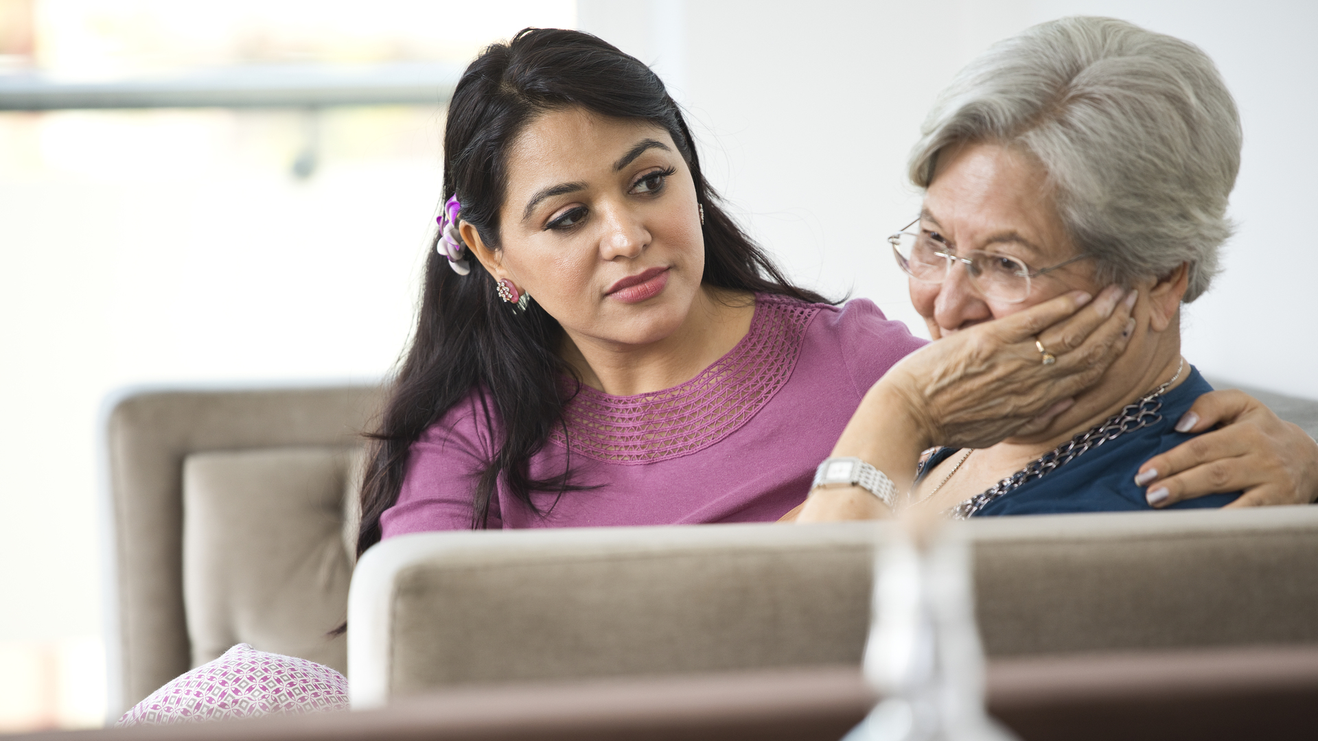 Woman consoling old mother at home