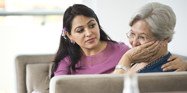 Woman consoling old mother at home