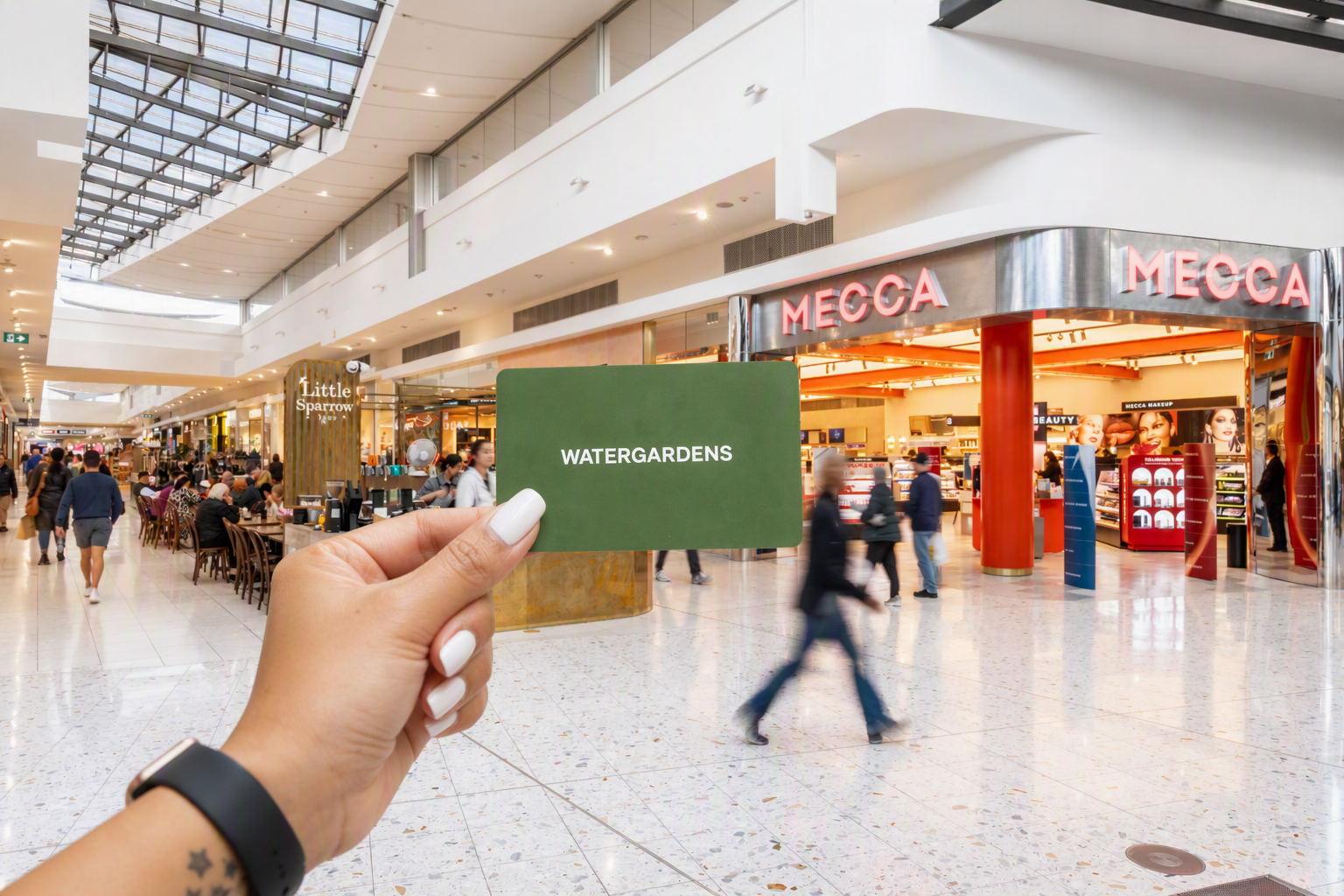 Woman's hand holding a Watergardens gift card.