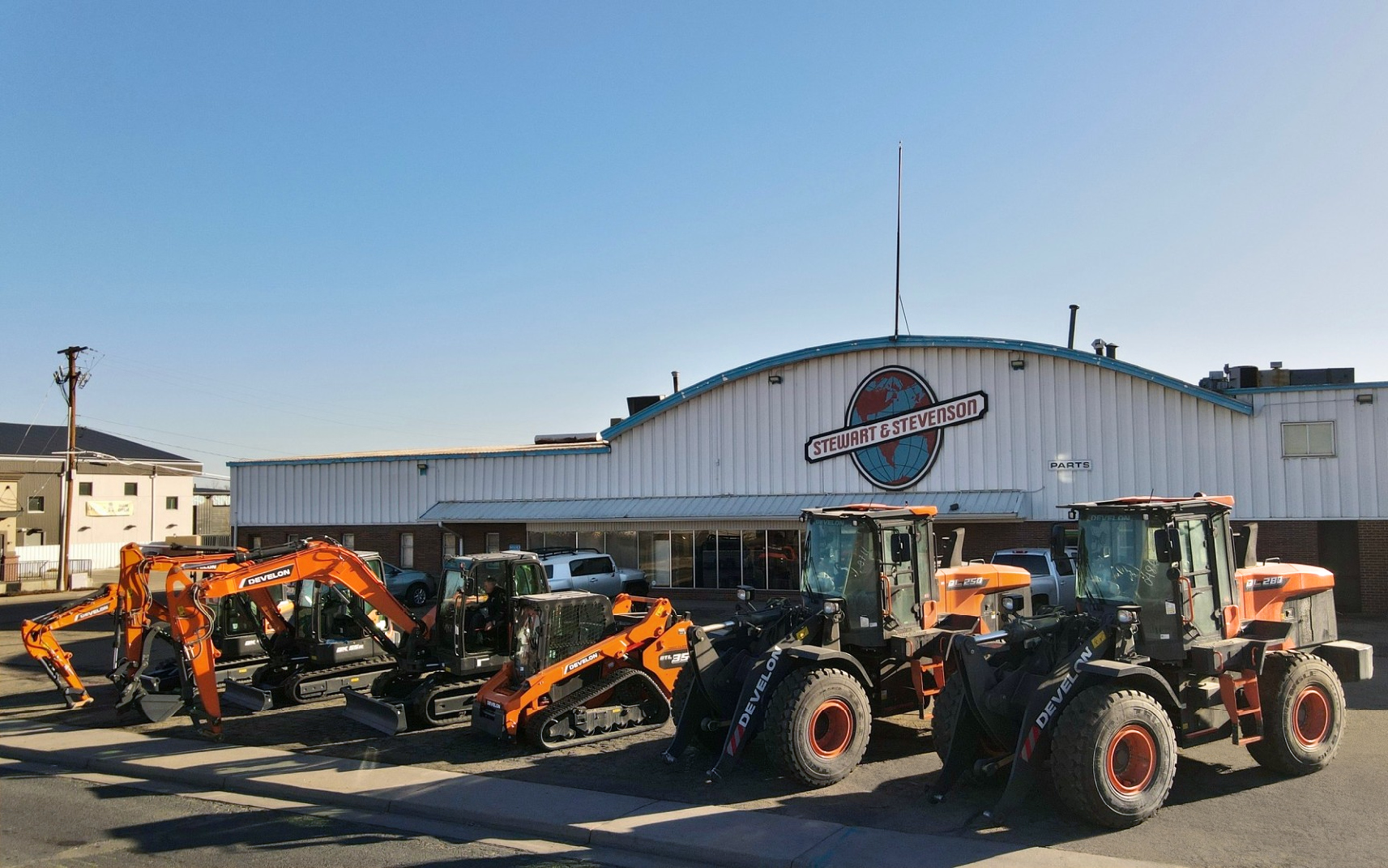 A row of DEVELON construction equipment outside a Stewart & Stevenson dealership.