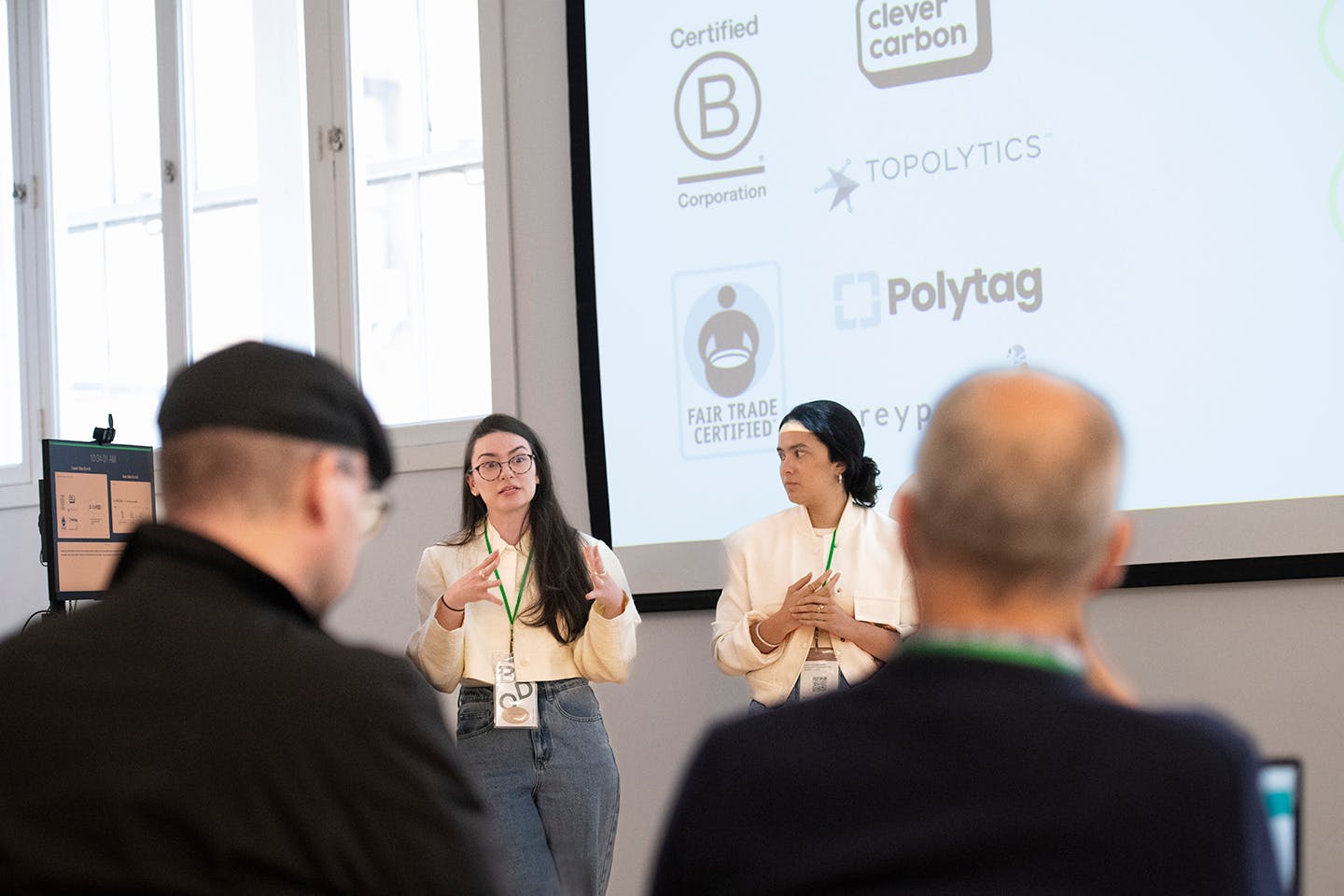 Irmak Senyurt and Lucía Jaramillo present their Awayste interface project at a podium and before a seated audience.