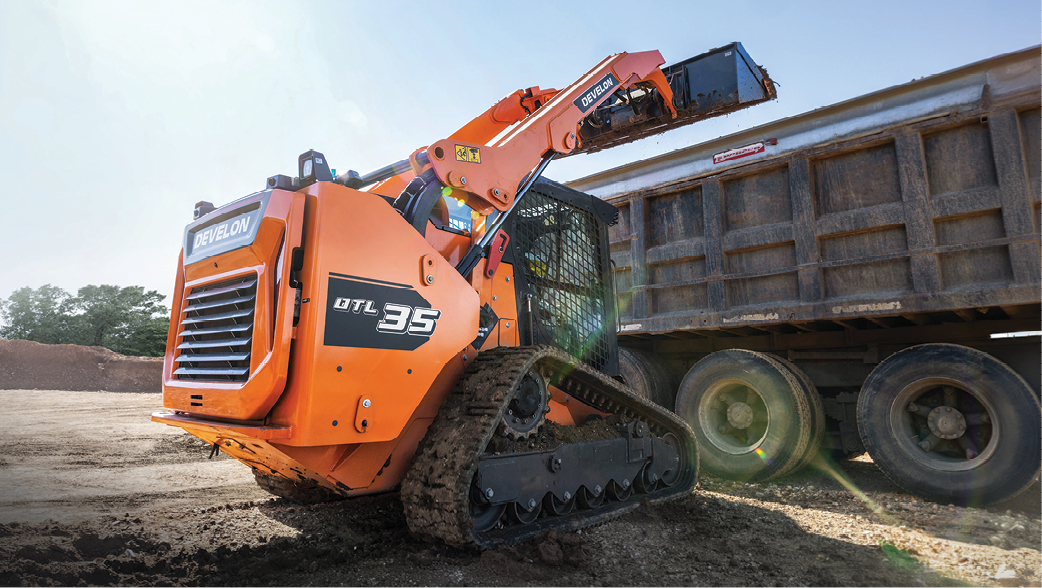 The DEVELON DTL35 compact track loader dumps material into a high-sided truck bed.