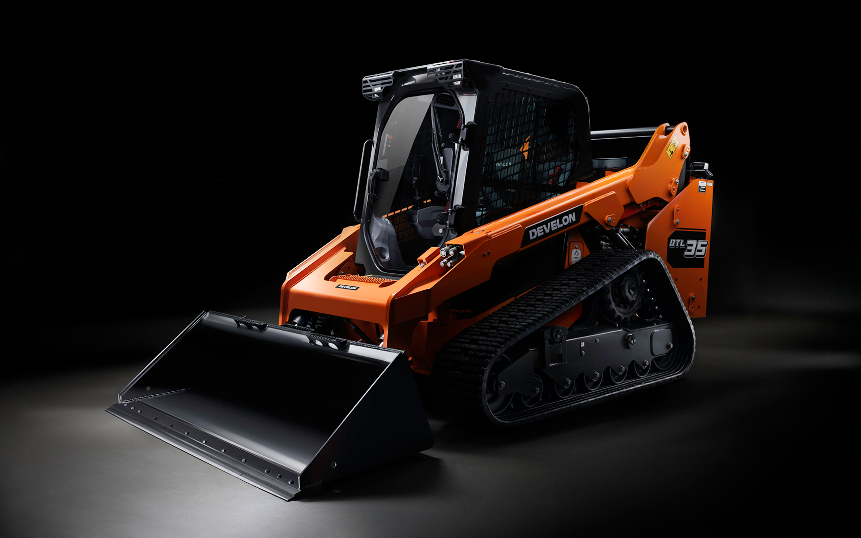 DEVELON's compact track loader with a spotlight on a black background