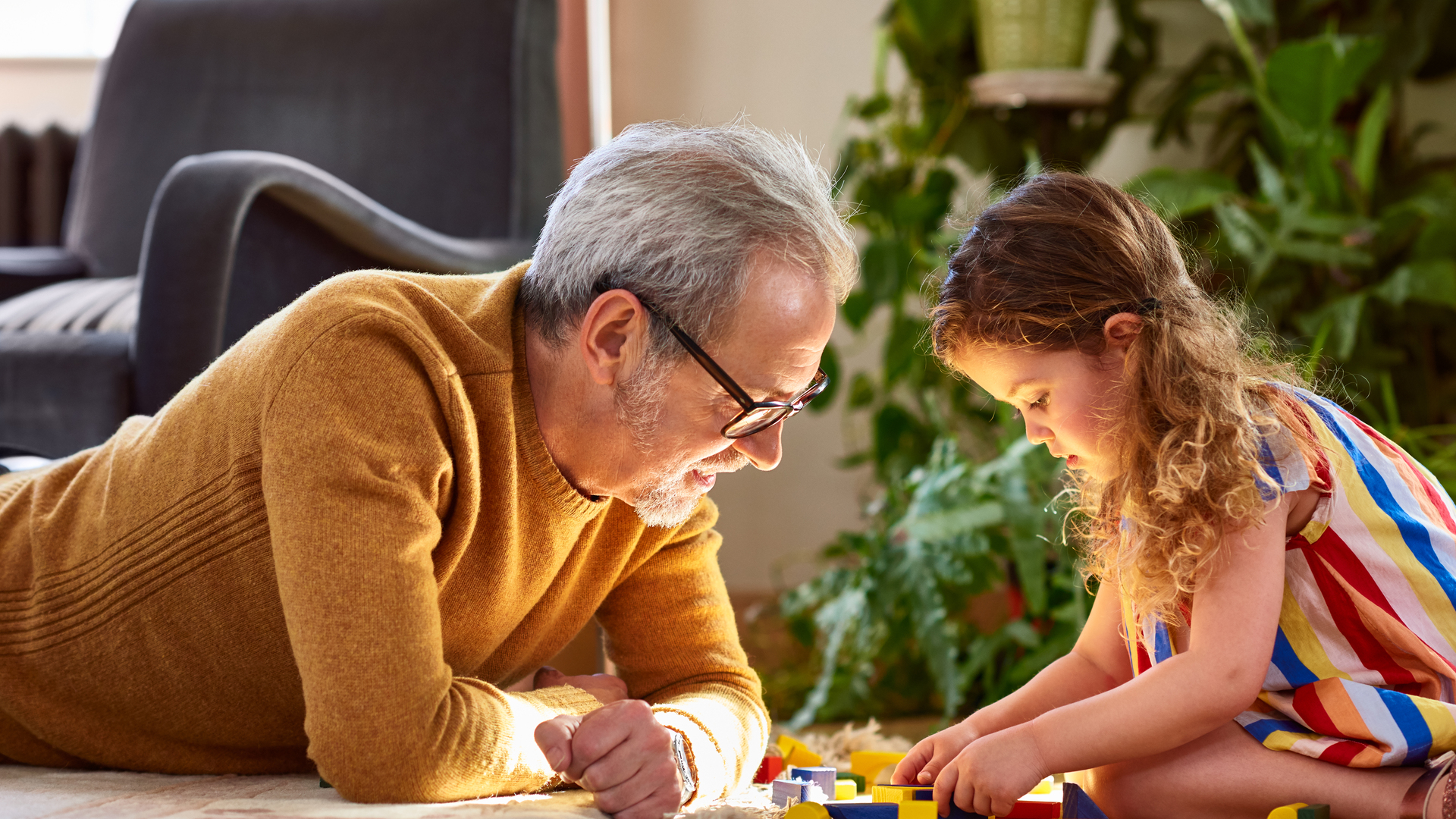 Granddaughter playing with wooden block and granddad watching