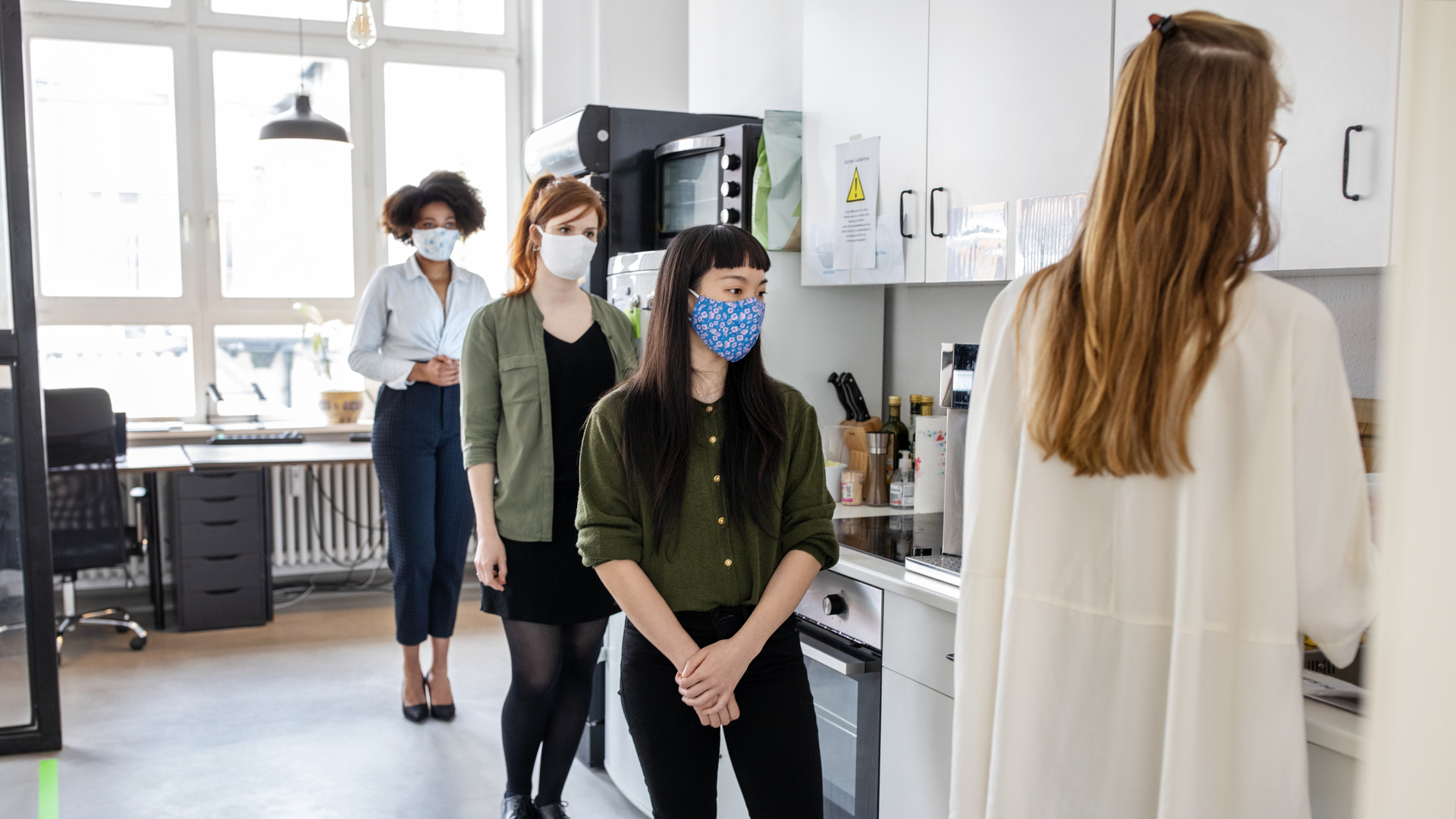 Businesswomen maintaining social distancing in office cafeteria