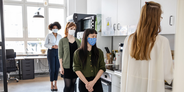 Businesswomen maintaining social distancing in office cafeteria