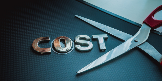 Stainless steel scissor next to word cost. Concept of cost-cutting