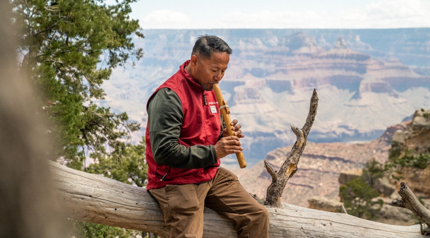 A Road Scholar instructor demonstrates a Native American flute in front of the Grand Canyon