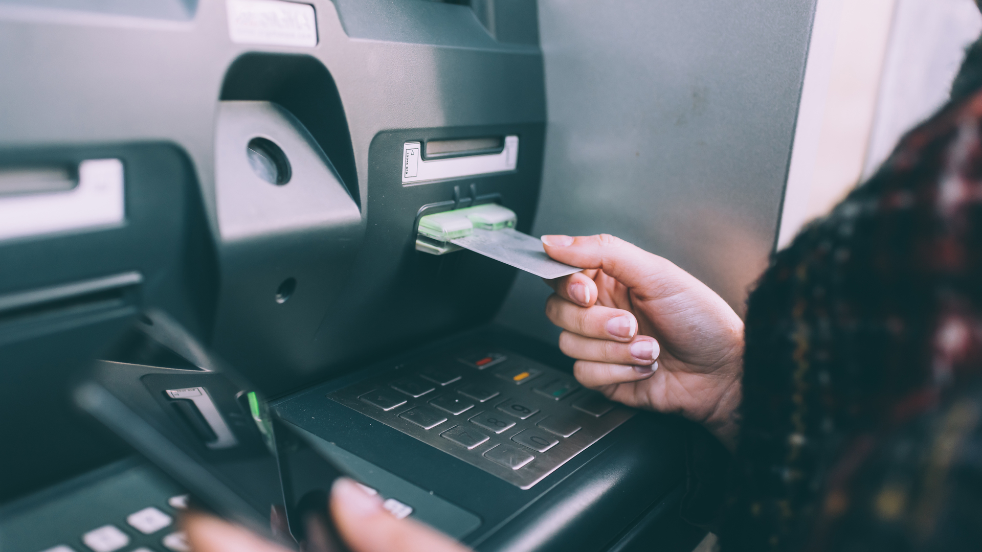 Hand of young woman inserting credit card into cash machine