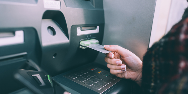 Hand of young woman inserting credit card into cash machine