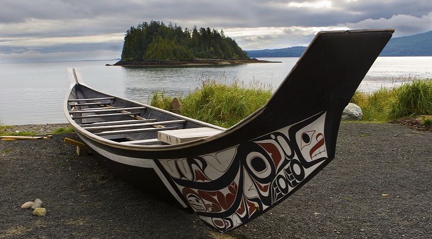 A boat pulled up on the shore with Native American designs on the side