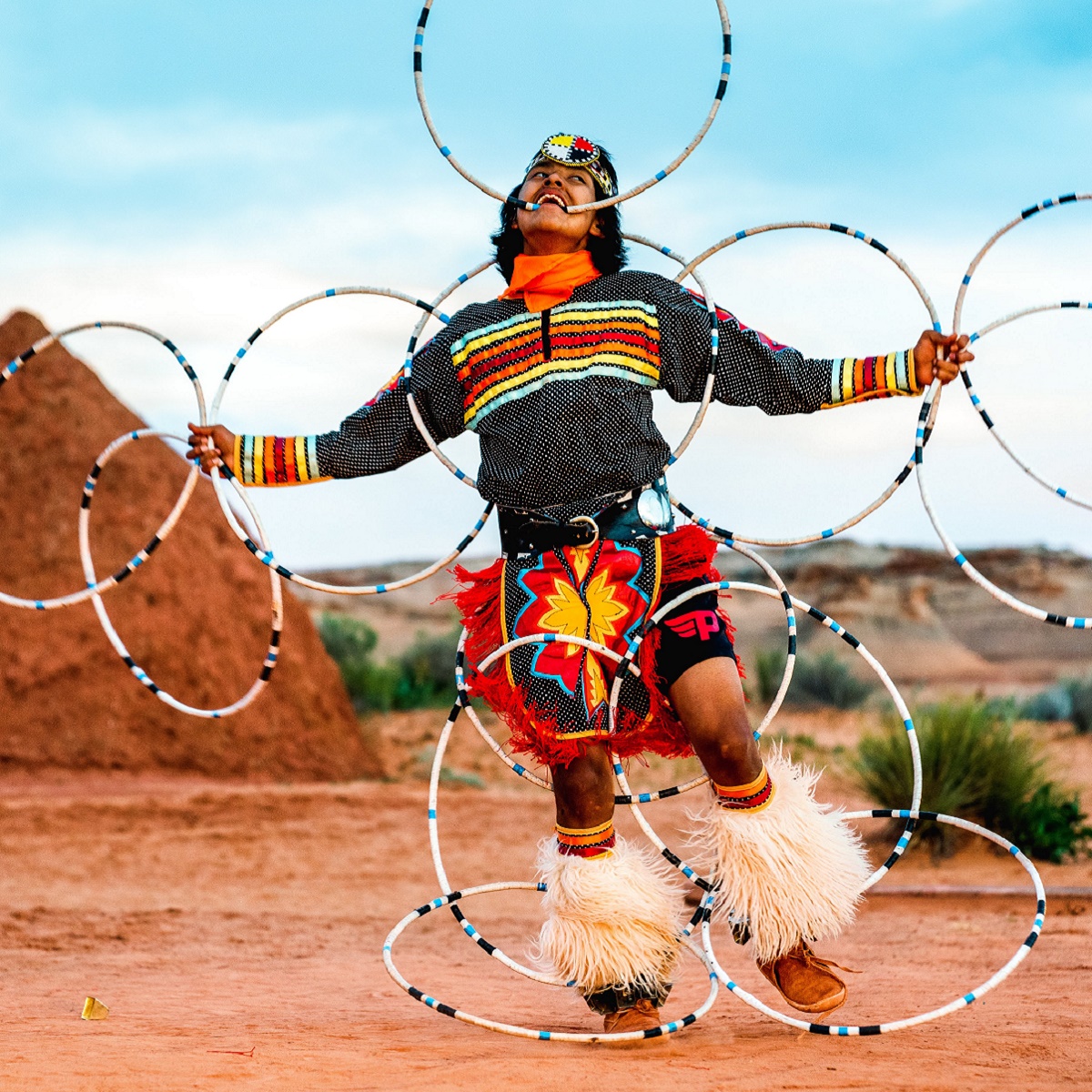 A Native American dancer performing a hoop dance with multiple hoops