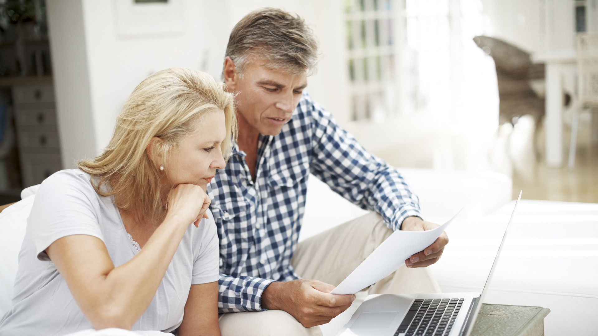 Mature couple doing paperwork and using computer