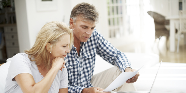 Mature couple doing paperwork and using computer