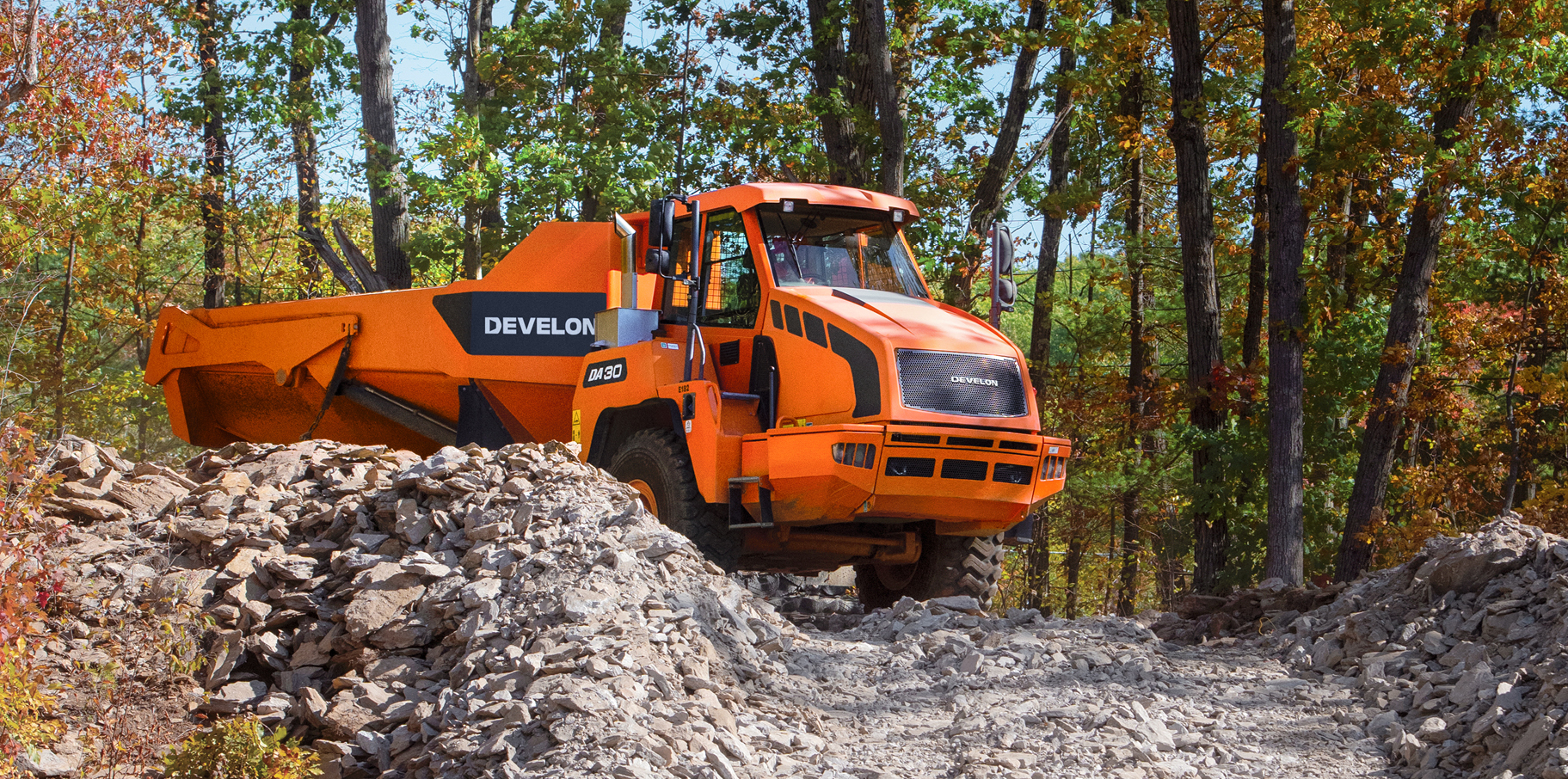 A DEVELON articulated dump truck hauling a load on a job site.