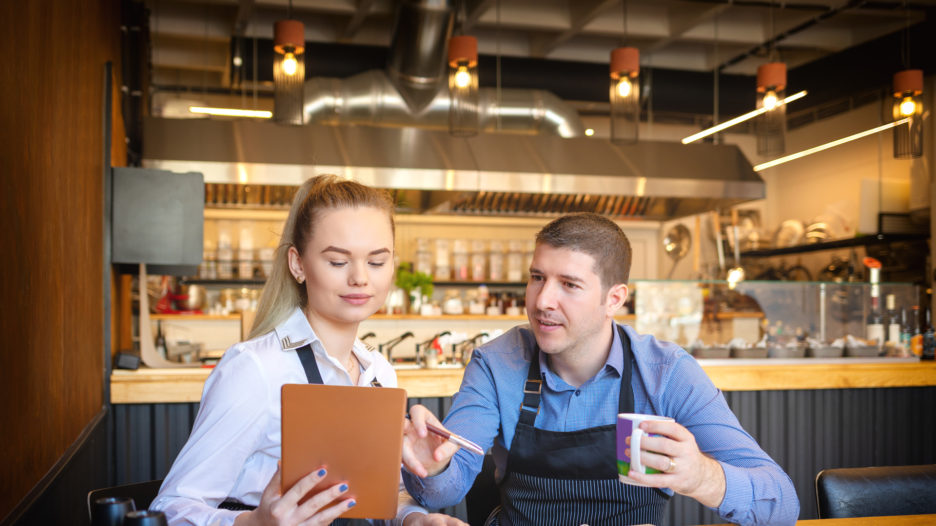 Young man and woman going through paperwork together in their restaurant. Small family restaurant owners discussing finance calculating bills and expenses of their small business.