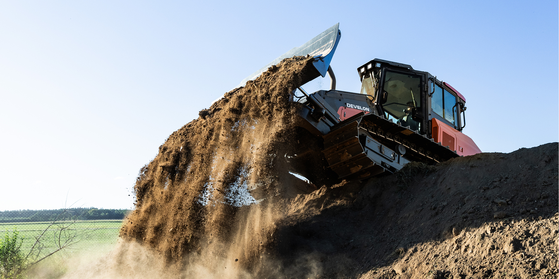 A DEVELON dozer pushes dirt at a job site.