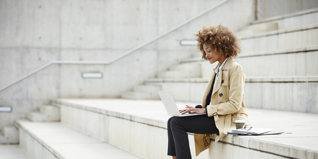 Businesswoman using laptop while sitting on steps