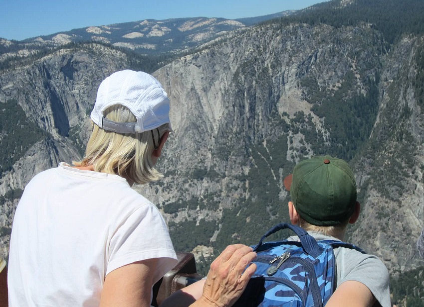 A grandparent and grandkid look at an impressive valley view in Yosemite