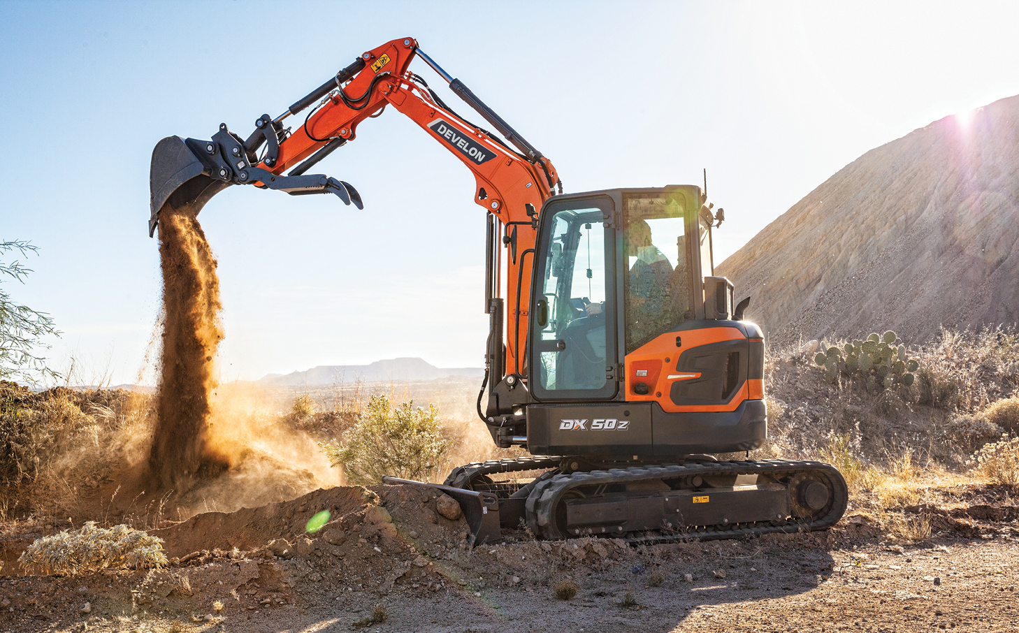 A DEVELON mini excavator dumping dirt on a job site.