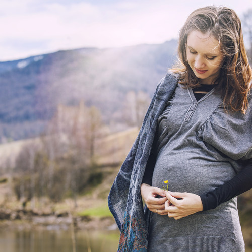 Young beautiful pregnant woman smiling on the background landscape nature portrait