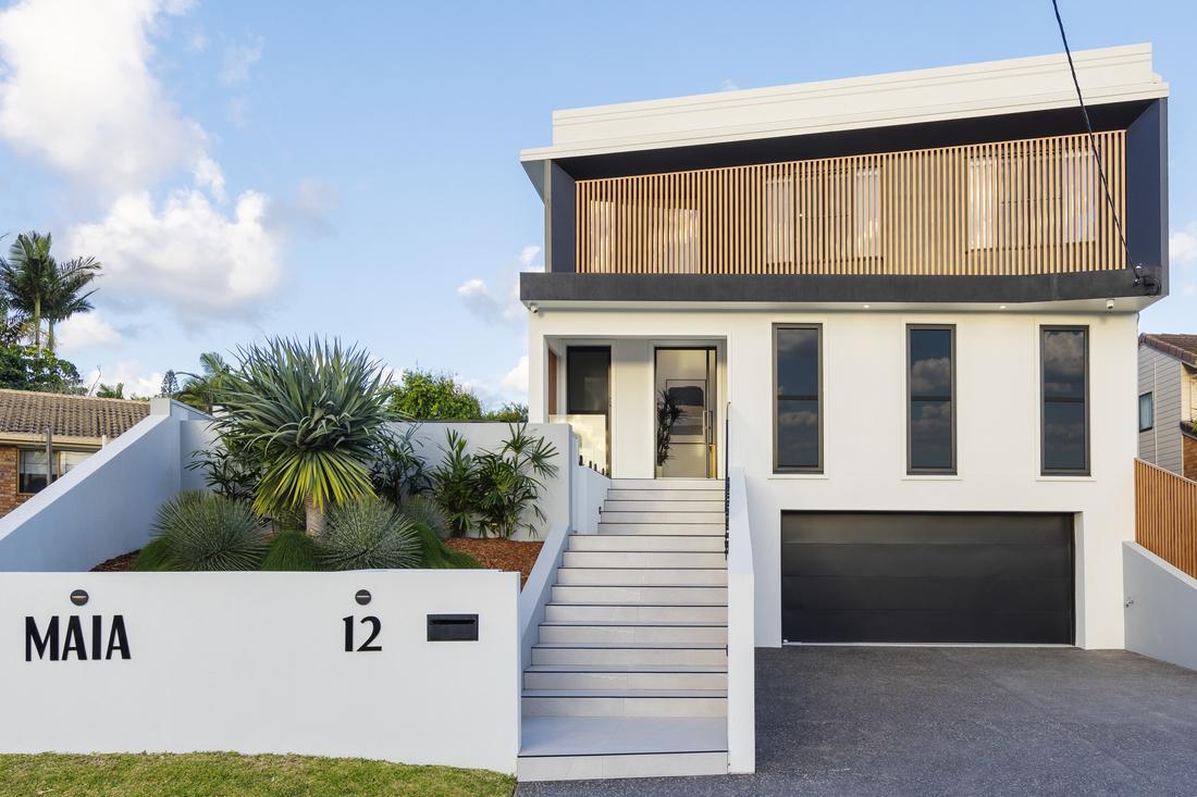Coolum Beach Prize Home. A white three level home in a cul-de-sac with gardens and stairs leading to the entrance.