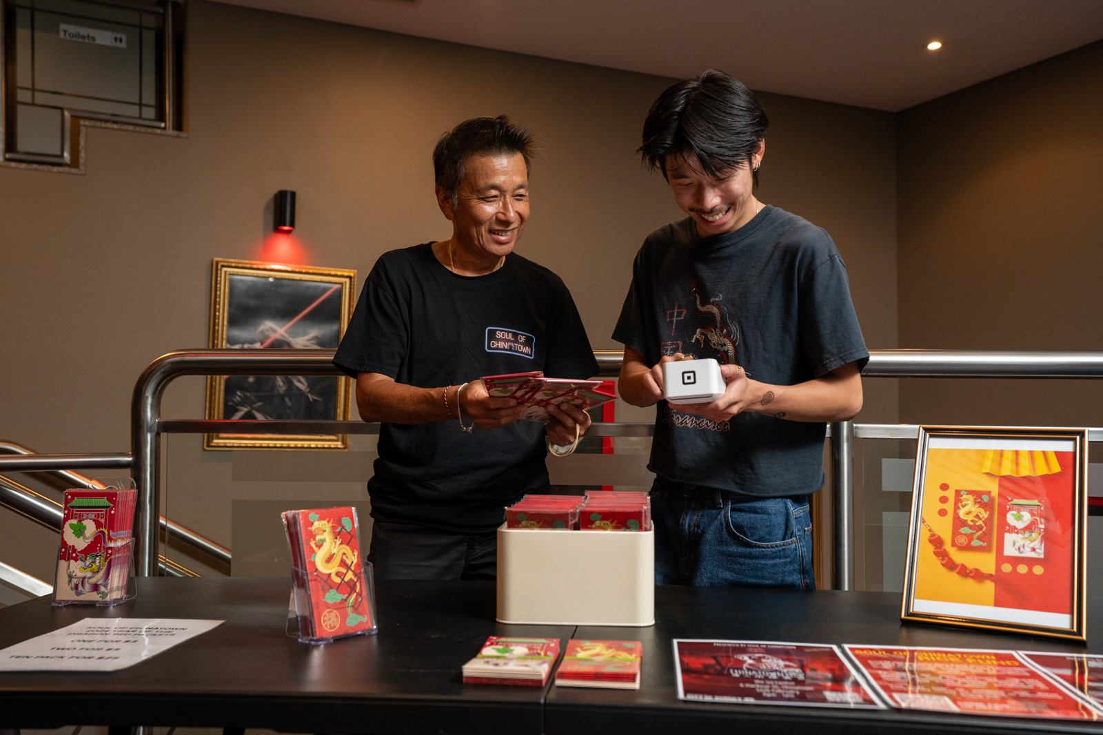 Two people standing behind a table, one holding chinese red packets and the other holding a Square Terminal