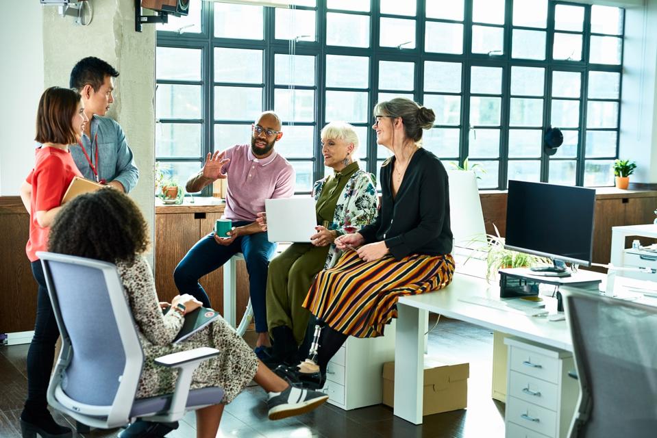 Business colleagues in meeting with female amputee sitting on desk