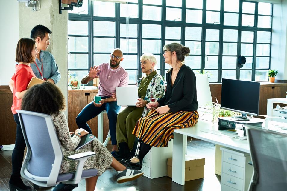 Business colleagues in meeting with female amputee sitting on desk