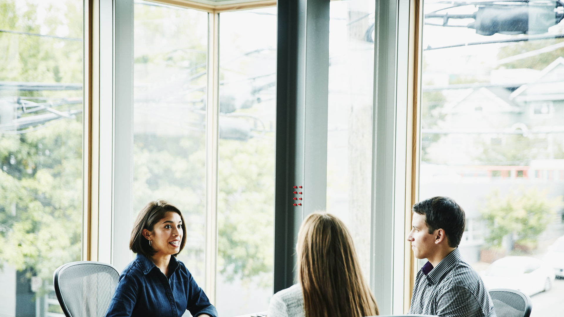 Smiling businesswoman in discussion with clients at office workstation