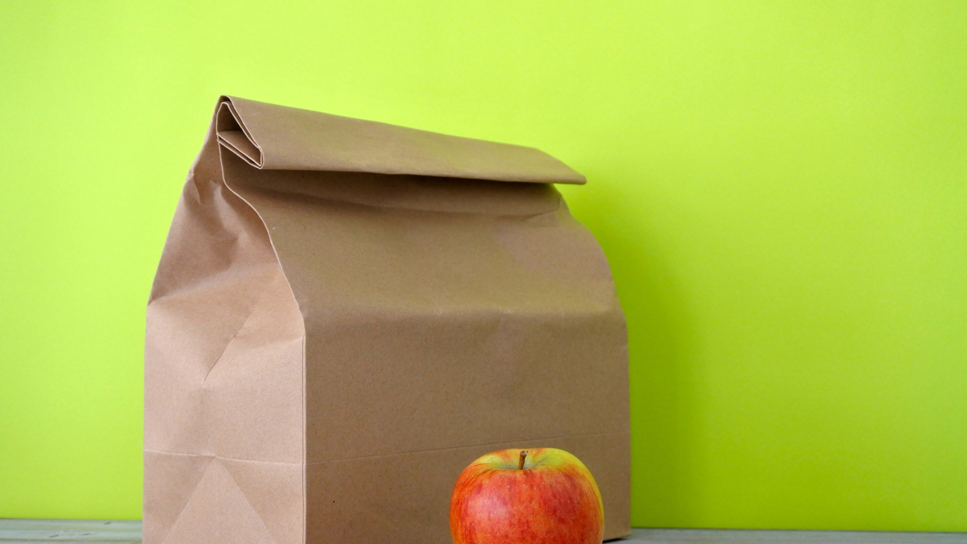 Lunch packed in a brown paper bag with red apple